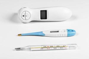 tres tipos de termómetros para medir la temperatura corporal en un paciente de fondo blanco