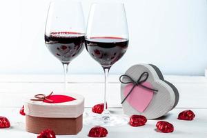 Glasses of red wine with gifts and chocolates photo