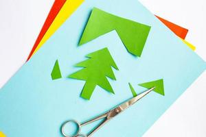 papel artesanal de colores con recorte de árbol de navidad y tijeras sobre fondo blanco foto