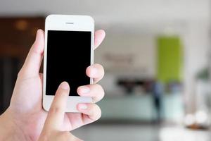 Hand holding smartphone with hotel reception blur background photo