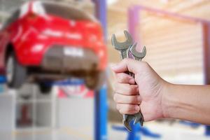 Car mechanic holding wrench at the car repair garage photo