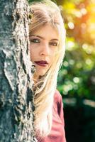 Blonde girl behind a tree photo