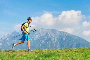 Young man practicing physical activity mountain and running with sticks photo