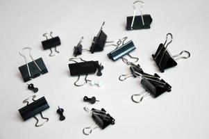 Black document clips and buttons scattered on a white background. Office tools. photo