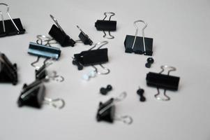 Black buttons and document clips and buttons randomly scattered on a white background. Office accessories, stationery. photo