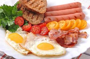 English breakfast - fried eggs, bacon, sausages and toasted rye bread photo