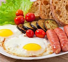 English breakfast - fried eggs, sausages, eggplant and tomatoes photo
