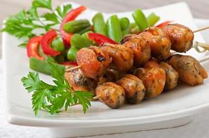 Fried mussels with onions on skewers c garnish of green beans and paprika photo