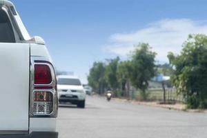 Rear side of pick up car driving on the asphalt road. with trees and other cars beside road. Under clear sky. photo