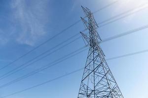 postes de alto voltaje en estructuras de acero pasan a través de cables. bajo el cielo azul. foto