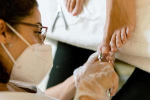 Beautician giving a pedicure painting her client's nails in a beauty centre. photo