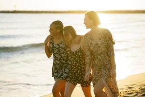 Delighted multiracial girlfriends walking on seashore photo