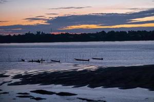 beautiful abstract twilight golden sun light sunset in sea behind island. silhouette fisherman boat. calm and romantic place in thailand photo