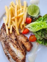 fish and potato chips steak with green vegetable salad and lemon. seafood cuisine with omega. photo