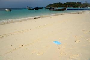 A disposable facemask thrown on the beach photo