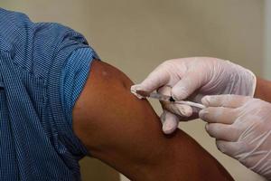 Close-up view of needle injecting vaccine on a man arm photo