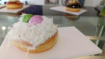 Donut glazed slice coconut and decorated with pink and green easter eggs on white plate photo