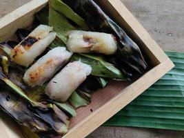 vista superior. arroz glutinoso relleno a la parrilla envuelto en hojas de plátano o arroz pegajoso con plátano y taro en un plato de madera. antiguo menú de estilo tailandés de arroz pegajoso. el nombre tailandés es khao niao ping foto