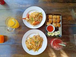 Pad Thai on the table served with orange juice, Roselle juice and fried spring rolls. popular Thai food, Top view photo