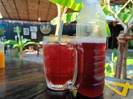 Iced roselle in glass on wooden table for healthy herbal drink and cool drink concept. photo