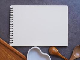 Recipe booklet, spoon, heart-shaped cup and wooden tray on cement background. photo