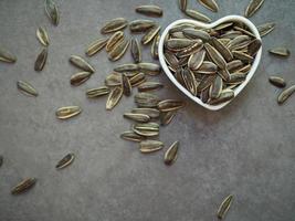 Sunflower seeds in a white heart-shaped cup on cement background. photo