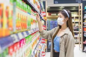 una joven asiática con cabello largo rubio dorado camina para comprar productos en el supermercado el fin de semana mientras usa una mascarilla médica para proteger el covid-19 en un nuevo concepto normal. foto