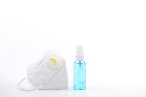 Alcohol spray and medical face mask on white background photo