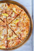 Hawaiian pizza is a Italian food which it made with tomato sauce, chopped pineapple, ham and cheese. photo