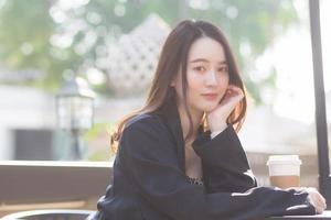 Asian beautiful woman in a black coat sitting in a cafe On sunny days photo