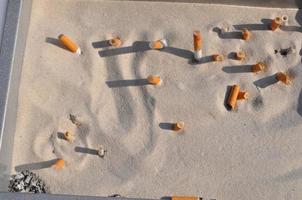 cigarette butts in the sand photo
