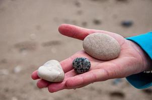 Person's hand holding three pebbles photo