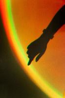 Shadow of womans hand. Rainbow reflection of sunbeam on wall. Hand touches rainbow. photo