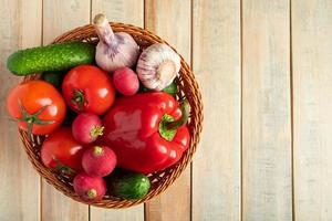 Set of fresh vegetables in a basket on a wooden background. The concept of healthy nutrition and diet. photo