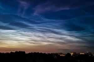 Noctilucent clouds in night sky. Rare atmospheric phenomenon over city. photo