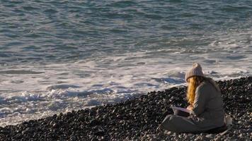 Frau liest eine Zeitung am Kiesstrand video