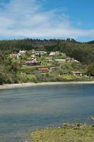 Vertical shot with a view of El Puntal. Residential houses on a hill, forest around. River arriving to Atlantic Ocean. Spot for bird watching. Asturias, Spain photo