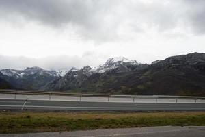 vista a la autovia que une asturias y leon. montañas con nieve, día nublado. concepto de previsión meteorológica al viajar. España foto