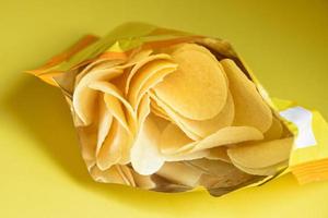 papas fritas de fondo amarillo, papas fritas es un bocadillo en un paquete de bolsas envuelto en plástico listo para comer y comida grasa o comida chatarra foto