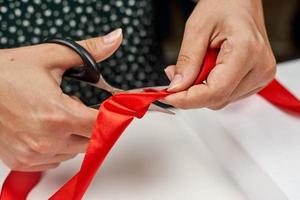 Hand of a woman cutting the ribbon by Christmas present at table photo