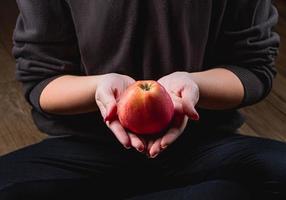 una mujer sostiene una manzana roja en sus manos. concepto de alimentación saludable