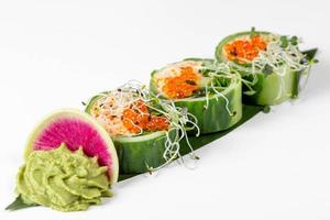 Fresh rolls with cucumber, avocado, crab, arugula and micro greens on a large green leaf with wasabi sauce photo