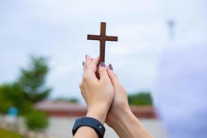 manos de mujer mientras reza por la religión cristiana, mujer casual rezando con una cruz, concepto de religión.