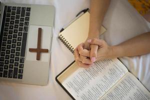 mano de mujer rezando en la sagrada biblia por la mañana. estudio biblia con adoración en línea.