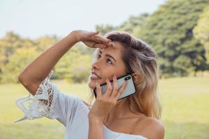 Retrato de una hermosa mujer sonriente enviando mensajes de texto y hablando con su teléfono