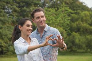 Beautiful happy young couple making heart shape with hand outdoor