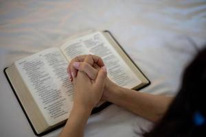 Woman hand praying on holy bible in the morning. Study bible with online worship. photo