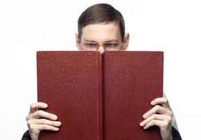 The man's face is covered by a large red notebook, on an isolated background photo