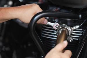 Mechanic using a wrench and socket on exhaust pipe of a motorcycle .maintenance,repair motorcycle concept in garage .selective focus photo