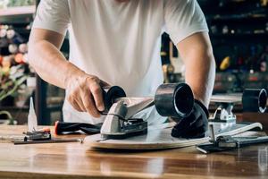 man repairing wheel of skateboard in workshop, Skateboard maintenance and repair concept. Selective focus photo